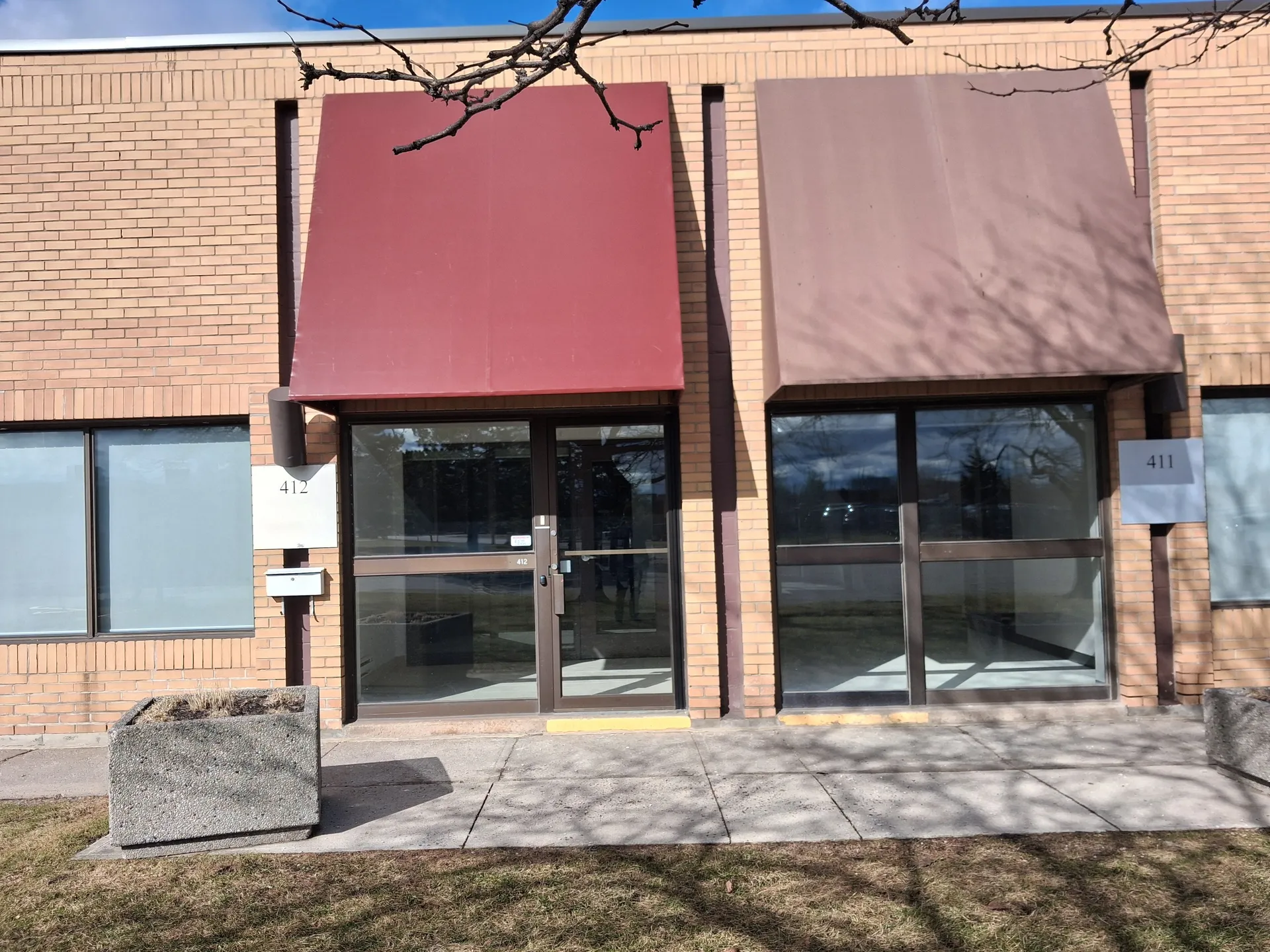 Crisp red storefront canopy beside a tan one with a planter in the foreground