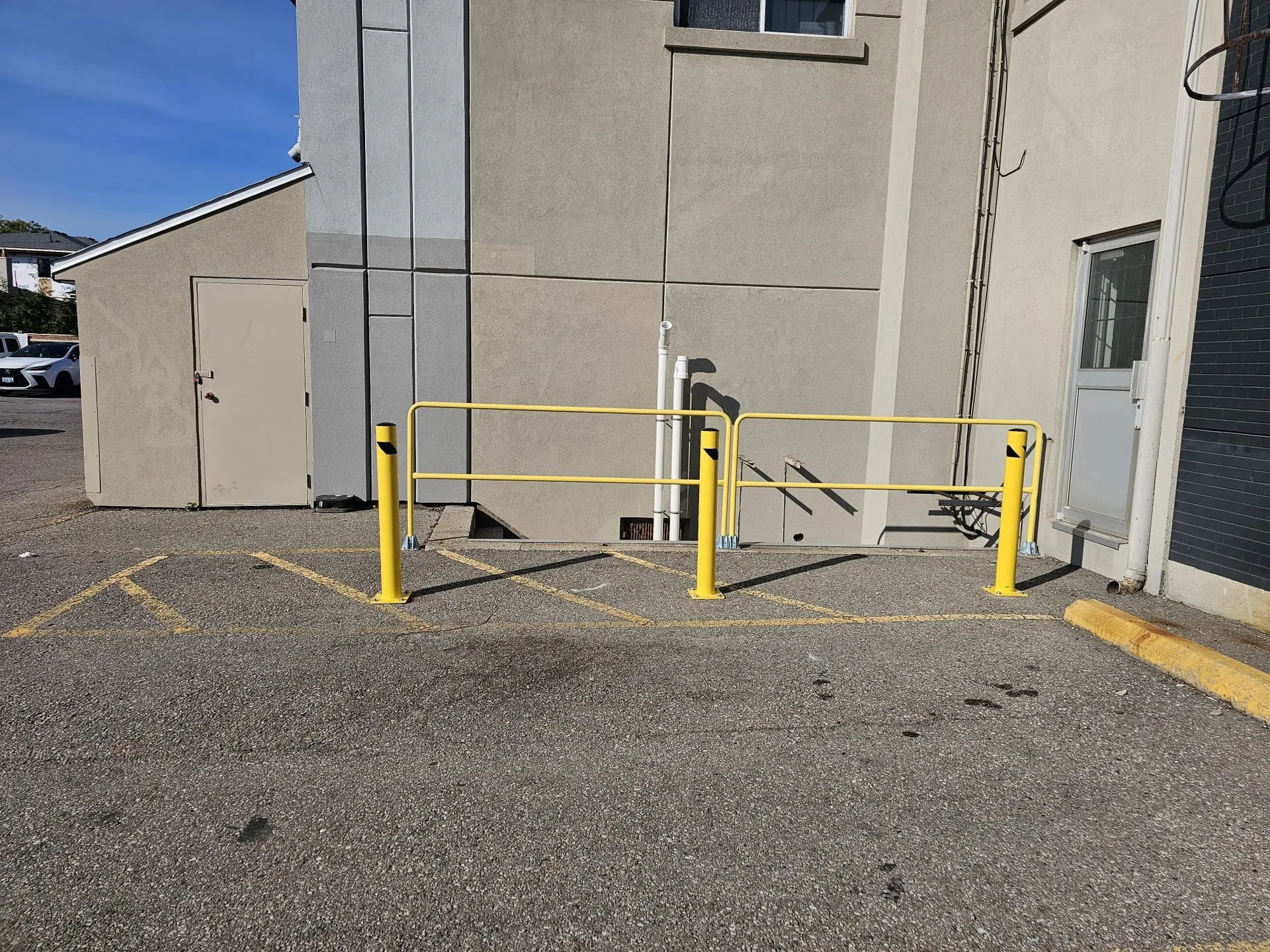 New yellow guardrail and bollards protecting a rear entrance and ramp