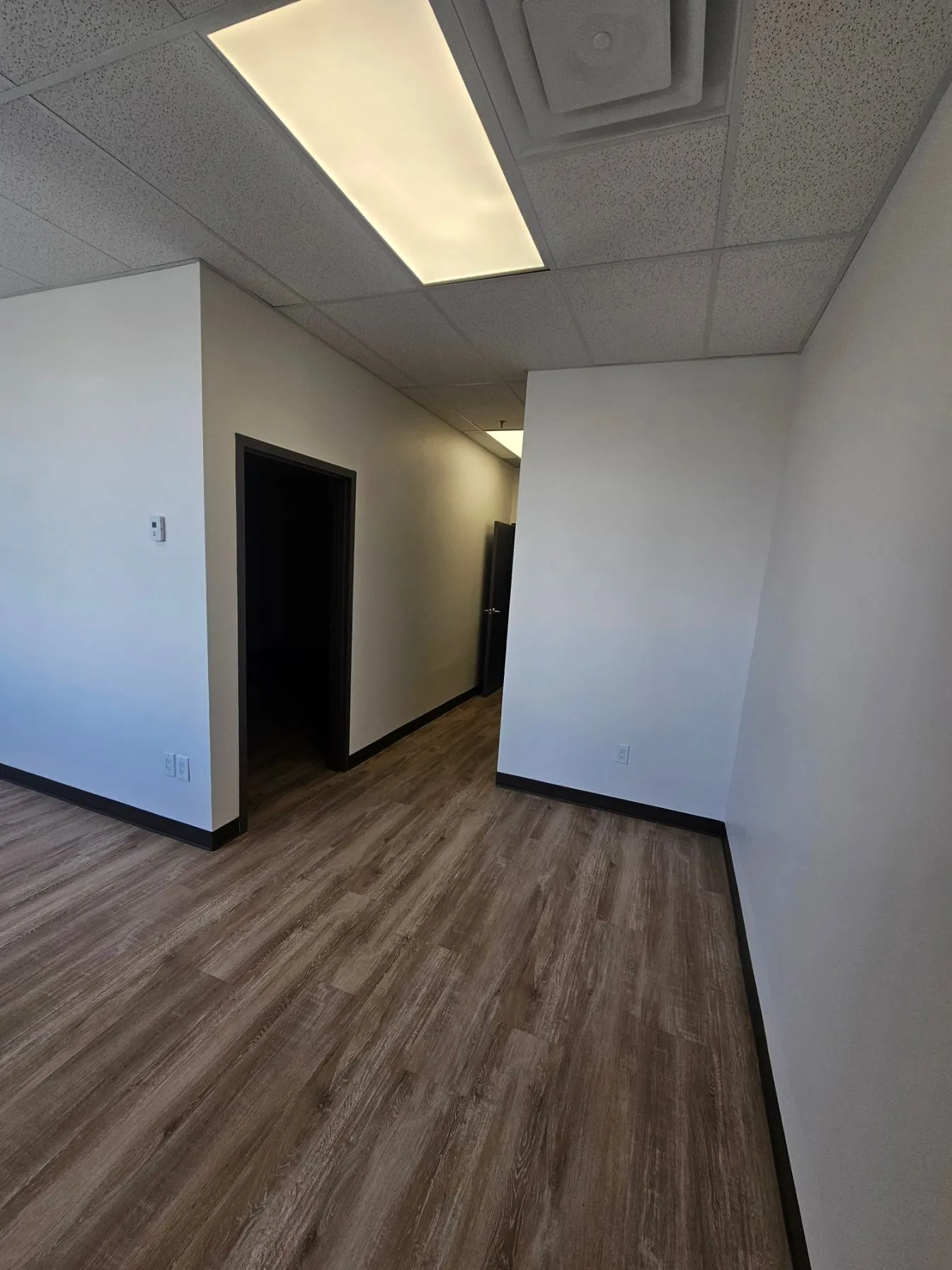 Room corner and hallway junction with new flooring and drop ceiling