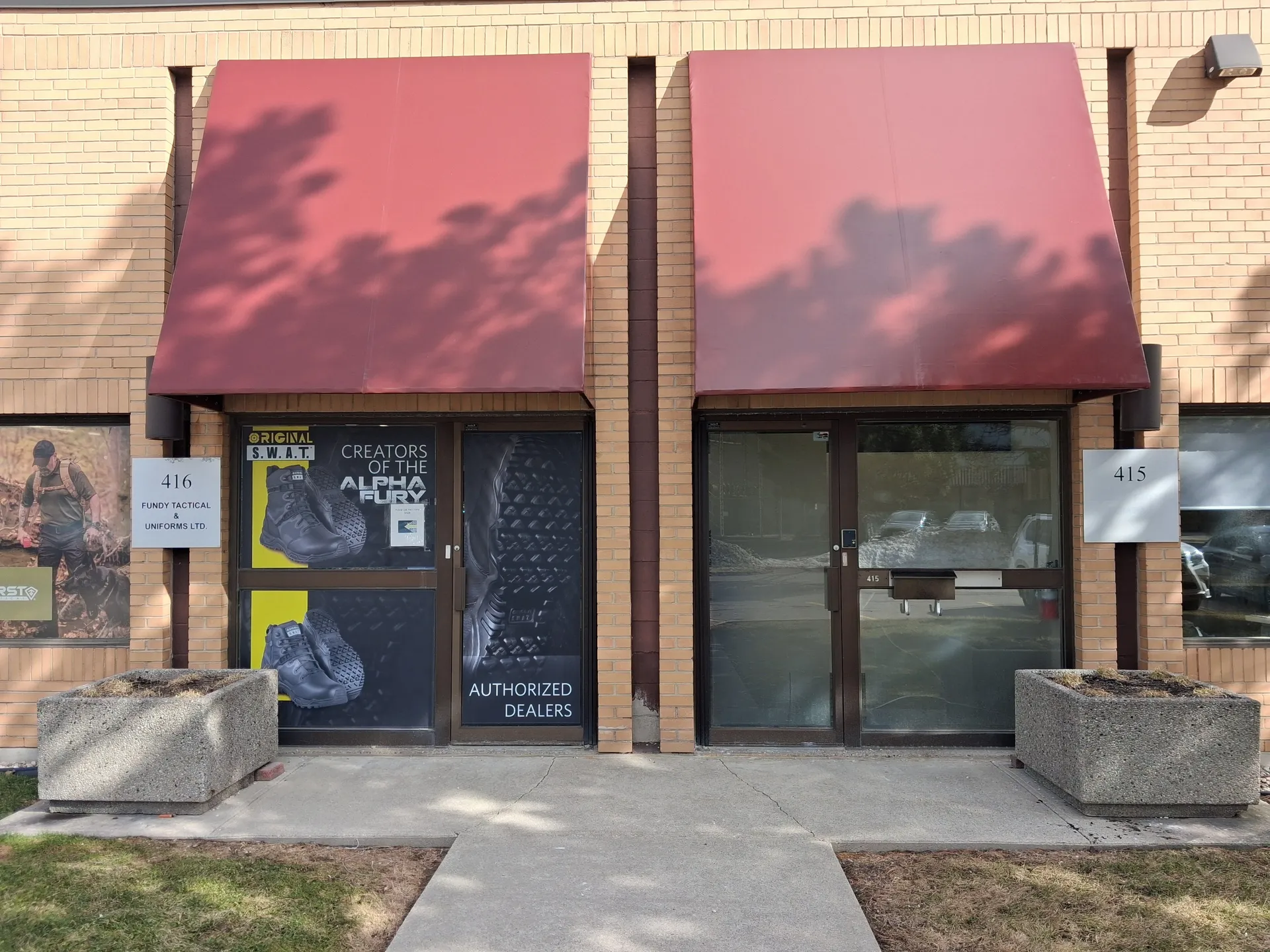 Fresh deep red canopies over brick storefronts with concrete planters