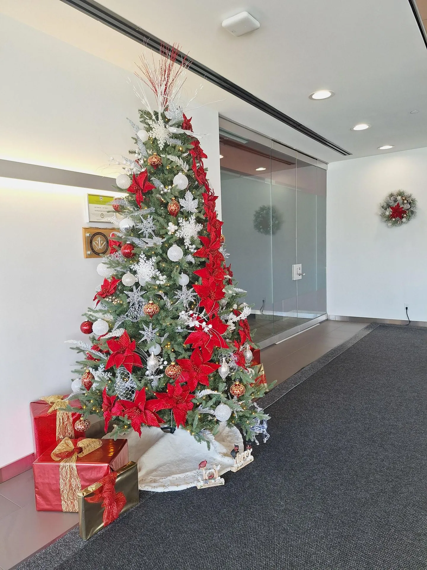 Red and white lobby Christmas tree with two matching wall wreaths in the background