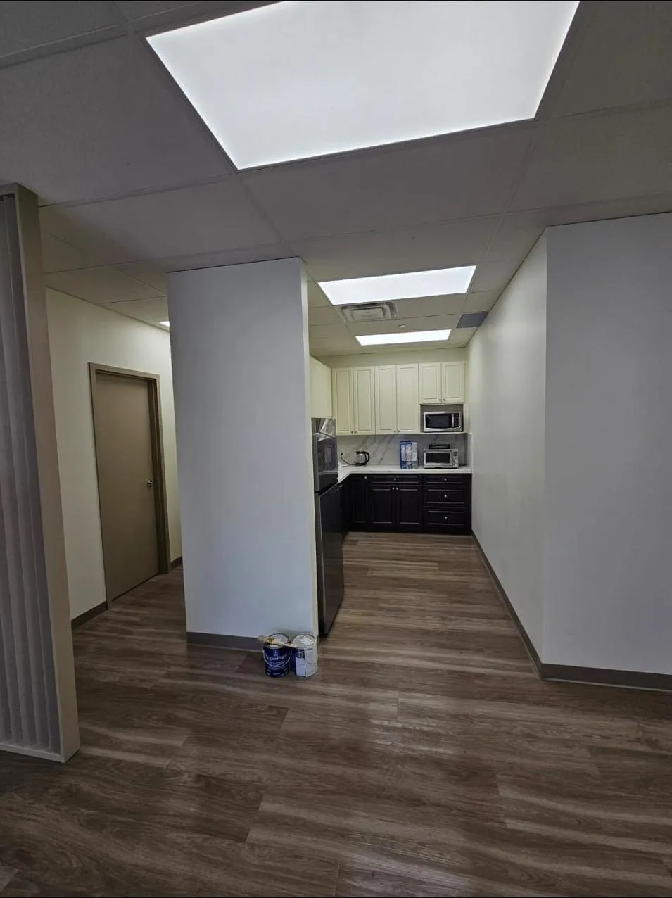 Kitchenette with white upper cabinets, dark base cabinets, and LVP flooring