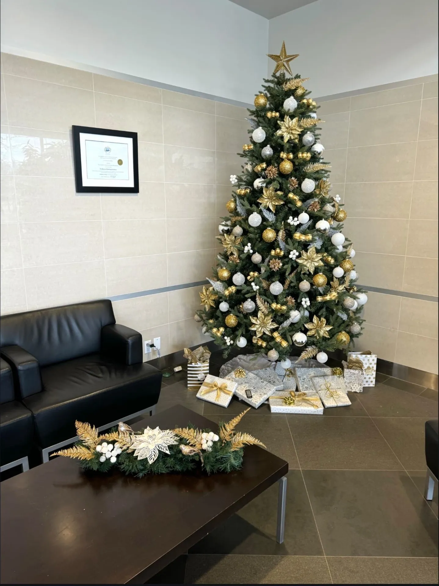 Gold and white themed holiday tree in an office lounge corner with coordinated wrapped gifts