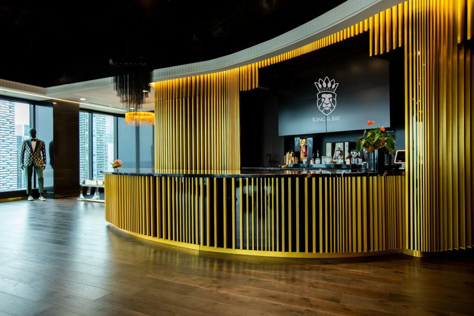 Curved gold vertical-slat reception desk with black backdrop and wood flooring in a showroom