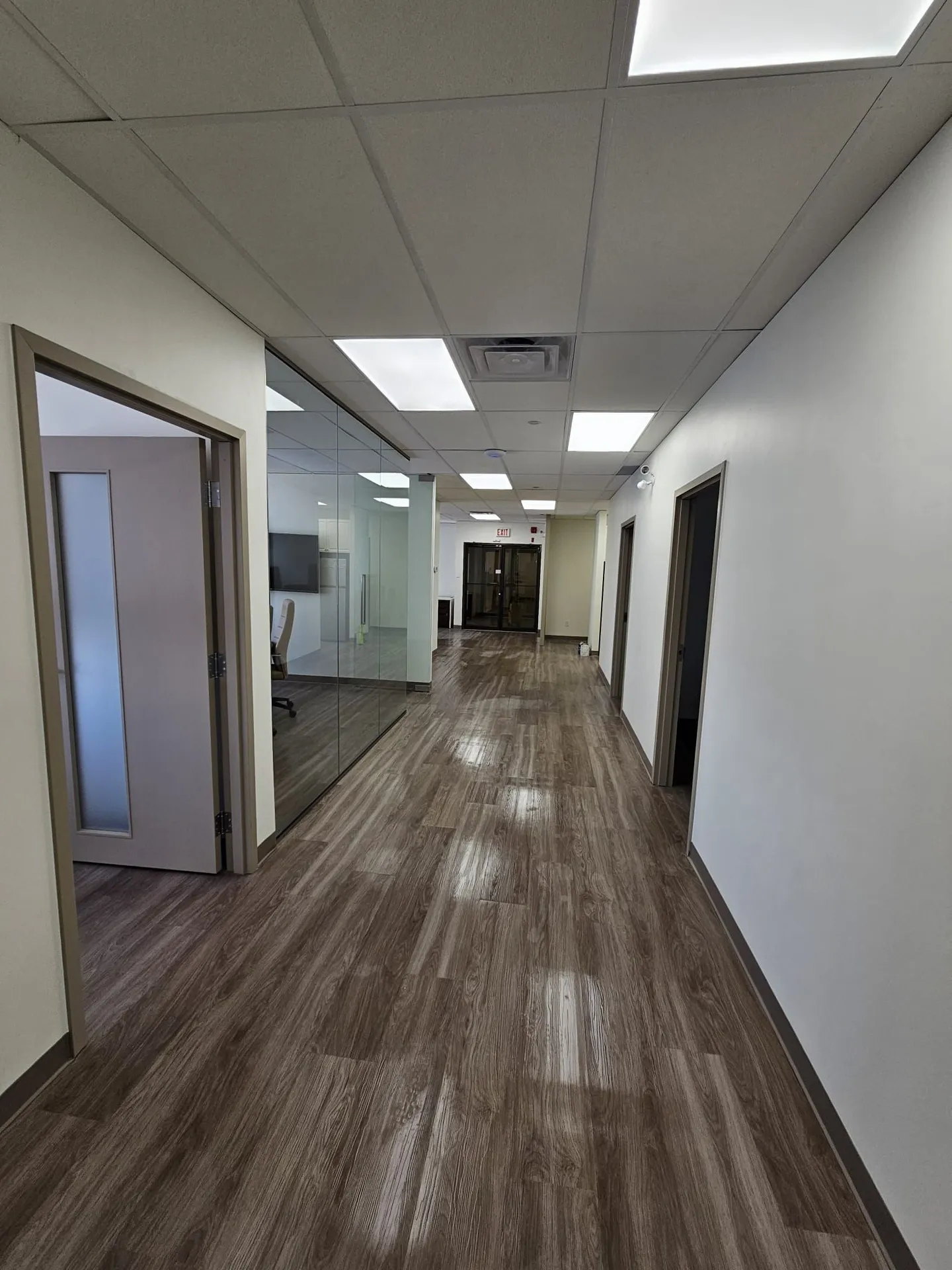 1050 Finch after: main corridor with glass-walled boardroom, dark LVP and new lighting