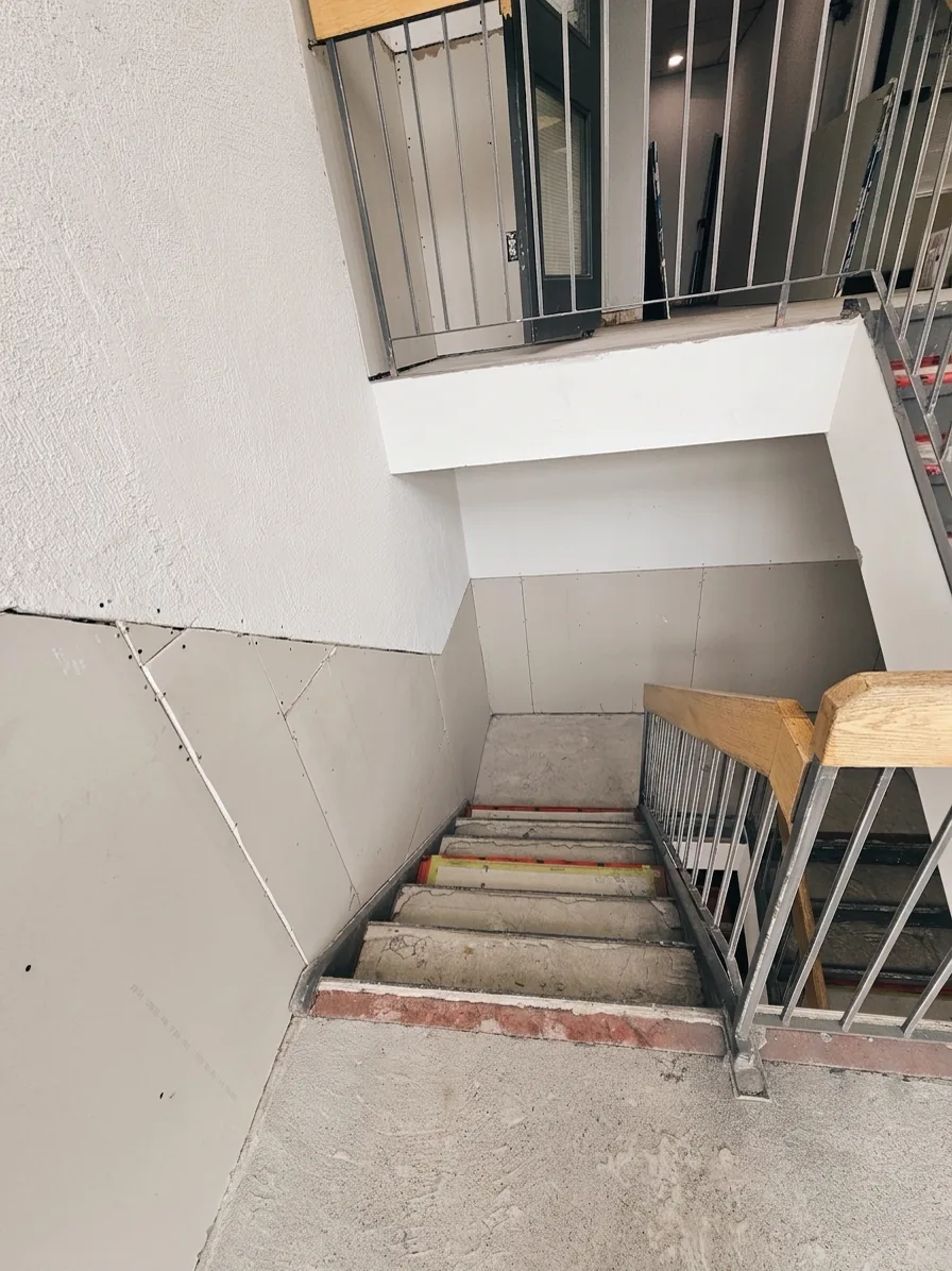 Stairwell before: bare concrete stairs and unpainted drywall